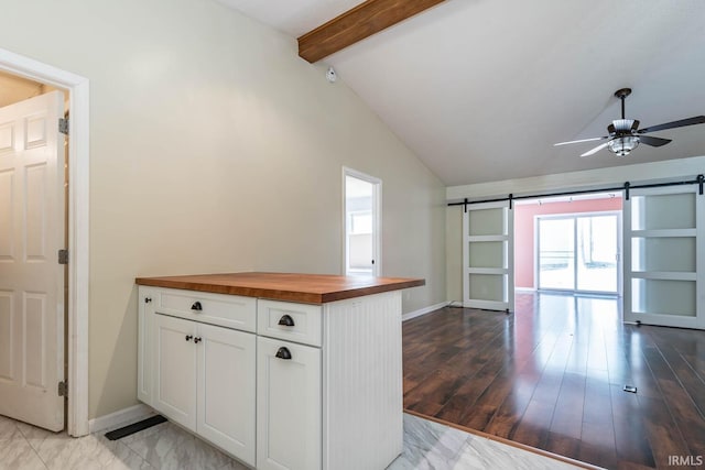 kitchen featuring a barn door, vaulted ceiling with beams, ceiling fan, and butcher block counters