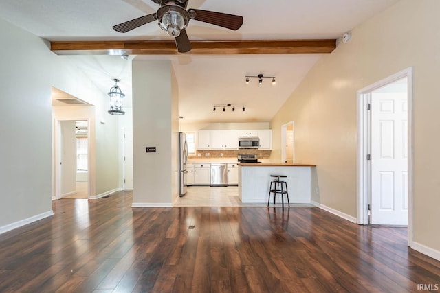 kitchen with tasteful backsplash, ceiling fan with notable chandelier, stainless steel appliances, and dark wood-style flooring