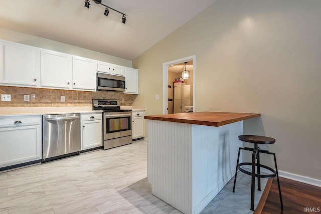 kitchen with white cabinetry, lofted ceiling, tasteful backsplash, and stainless steel appliances