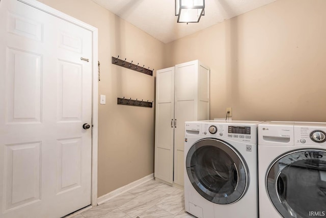 laundry room with baseboards, cabinet space, marble finish floor, and washer and clothes dryer