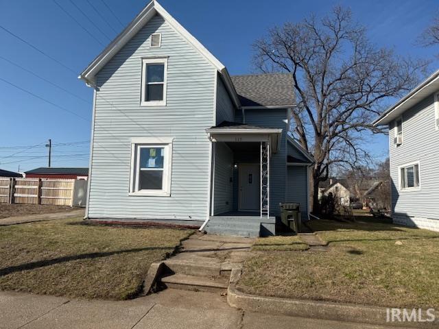 traditional home featuring a front lawn and fence