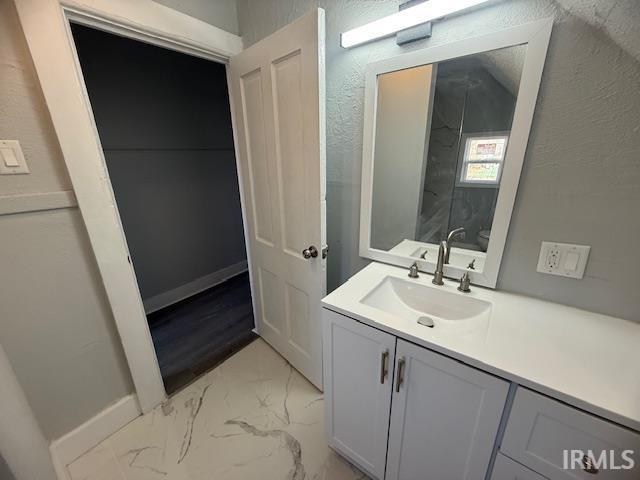 bathroom featuring vanity, toilet, baseboards, and marble finish floor