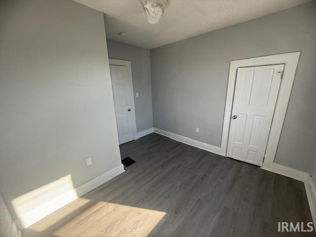 unfurnished bedroom with dark wood-type flooring and baseboards