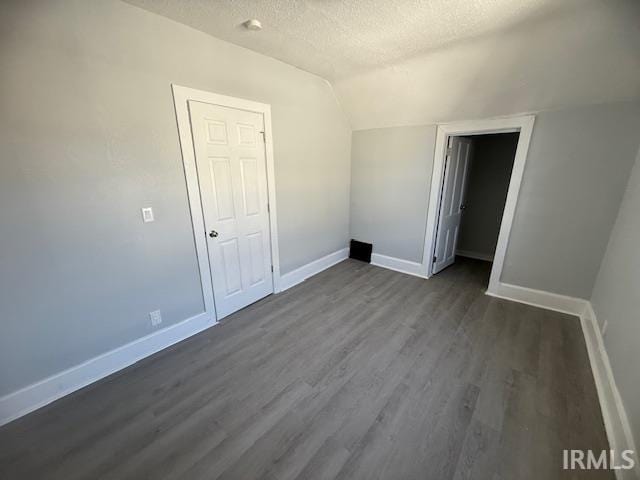 unfurnished bedroom featuring a textured ceiling, dark wood-type flooring, and baseboards