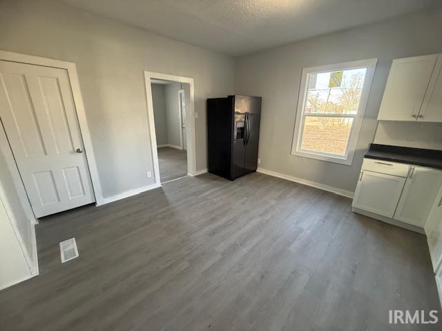 unfurnished bedroom with dark wood finished floors, a textured ceiling, baseboards, and black fridge