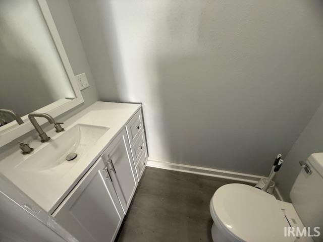 bathroom featuring vanity, toilet, baseboards, and concrete flooring