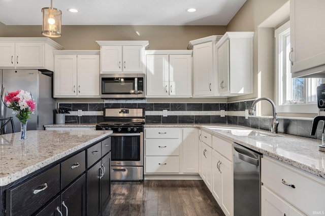 kitchen featuring dark wood-type flooring, dark cabinetry, white cabinets, stainless steel appliances, and a sink