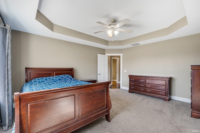 bedroom with baseboards, visible vents, a tray ceiling, ceiling fan, and light colored carpet