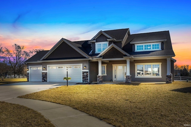 craftsman-style house featuring an attached garage, fence, a front yard, stone siding, and driveway