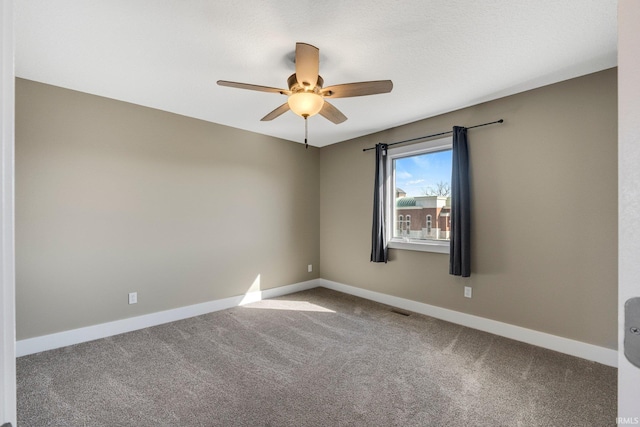 carpeted empty room with baseboards, visible vents, and ceiling fan