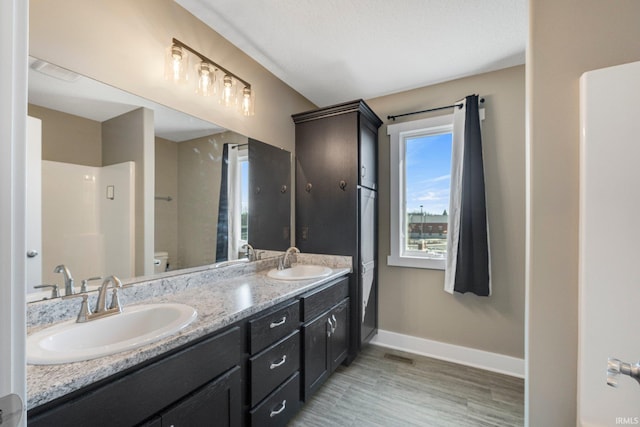 full bathroom with a sink, baseboards, toilet, and double vanity