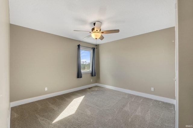 spare room with baseboards, light carpet, and a ceiling fan