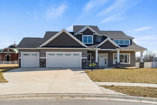 craftsman-style home featuring a front lawn, an attached garage, fence, and driveway