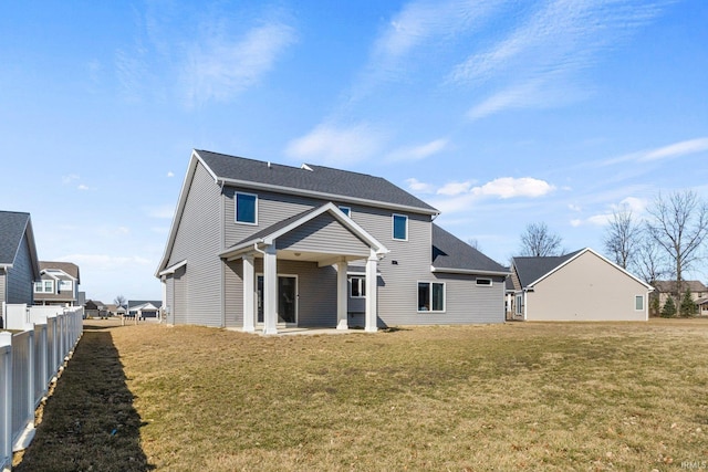 back of property with a lawn and fence