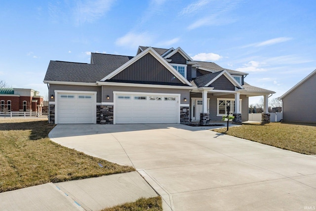 craftsman-style house featuring stone siding, a front lawn, concrete driveway, and an attached garage