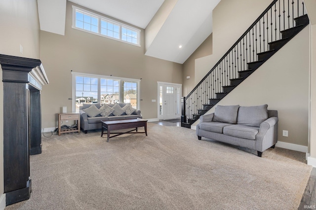 carpeted living area with stairway, baseboards, and a towering ceiling