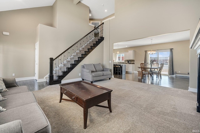 carpeted living room featuring stairway, wood finished floors, baseboards, an inviting chandelier, and a baseboard heating unit