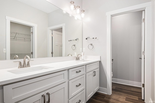 bathroom with double vanity, wood finished floors, baseboards, and a sink