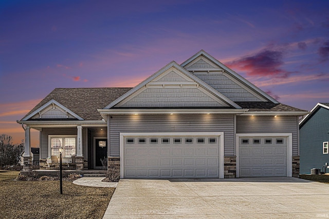 view of front of home featuring a porch, stone siding, a garage, and driveway