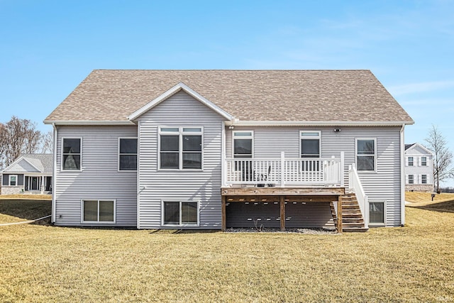 back of property with a lawn, roof with shingles, a deck, and stairs