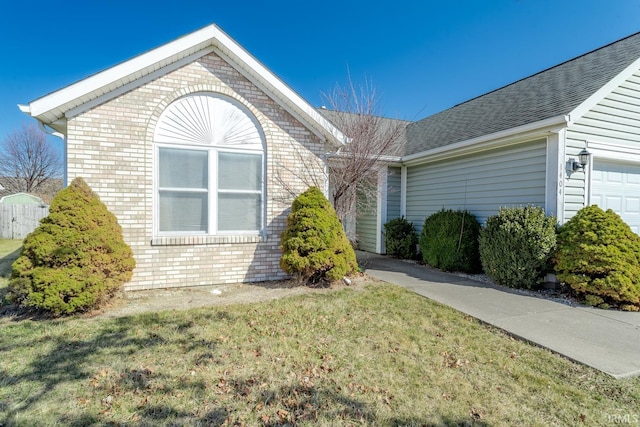 view of front of house with brick siding, a garage, a shingled roof, and a front lawn