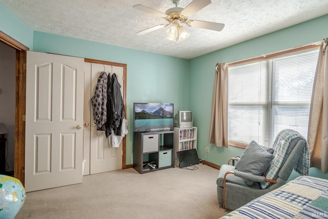 bedroom featuring baseboards, carpet, a closet, a textured ceiling, and a ceiling fan