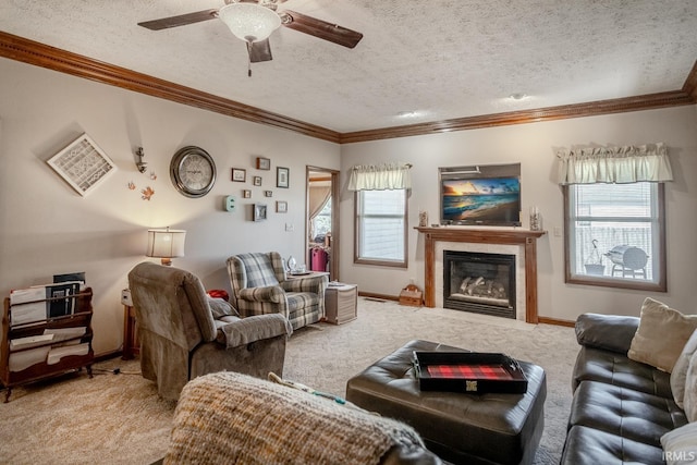 carpeted living room featuring a ceiling fan, baseboards, ornamental molding, a textured ceiling, and a glass covered fireplace