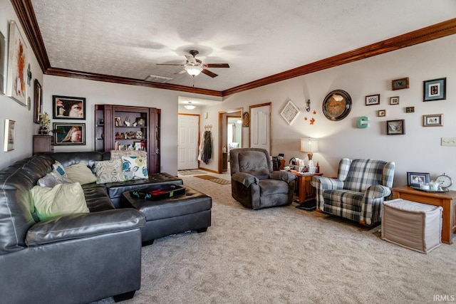 living area with visible vents, a ceiling fan, a textured ceiling, crown molding, and carpet flooring