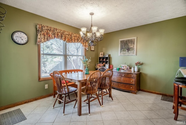 dining room with a chandelier, light tile patterned floors, a textured ceiling, and baseboards