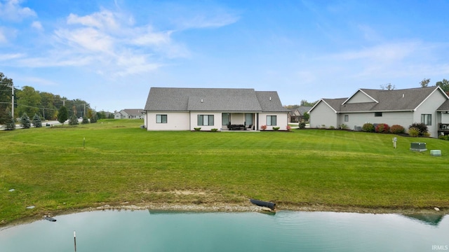 rear view of property with a water view, a lawn, and a patio area