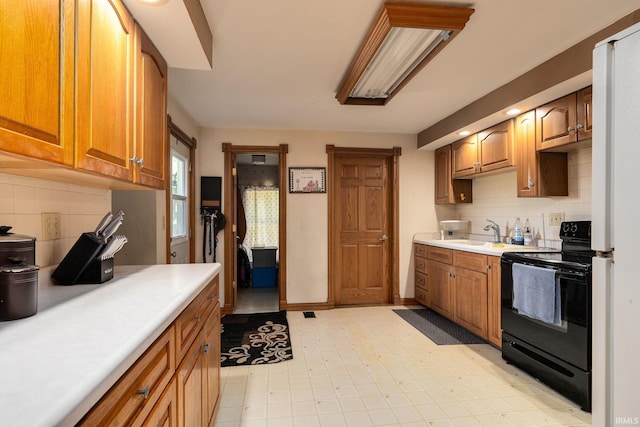 kitchen featuring tasteful backsplash, black range with electric stovetop, light floors, light countertops, and a sink