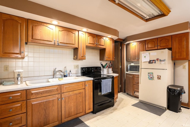 kitchen with electric range, light countertops, freestanding refrigerator, and a sink