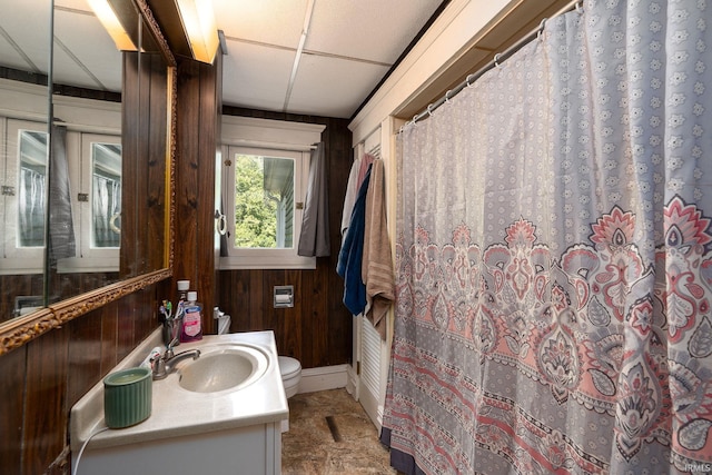 bathroom with a shower with shower curtain, wooden walls, vanity, and toilet