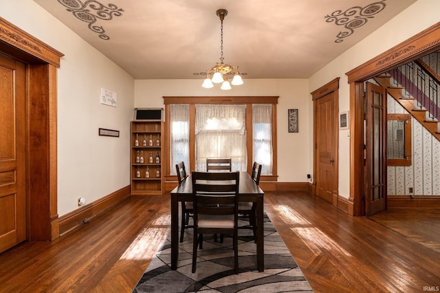 dining space with baseboards, dark wood-type flooring, a notable chandelier, and stairs