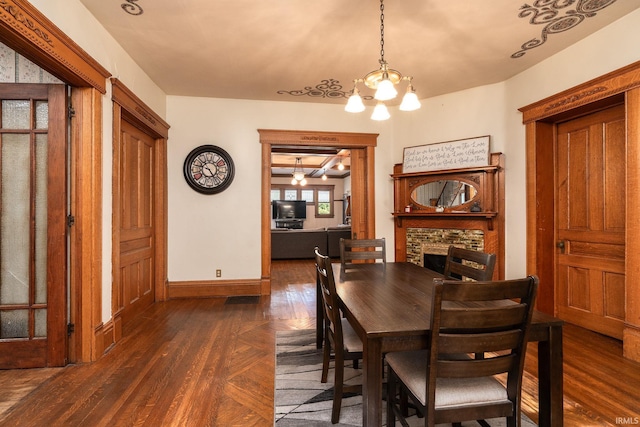 dining area with a chandelier, a fireplace, parquet floors, and baseboards