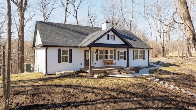 modern farmhouse style home with cooling unit, covered porch, roof with shingles, and a chimney