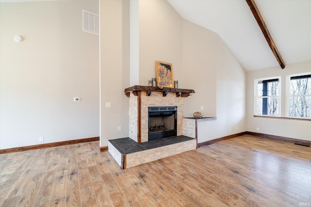 unfurnished living room with visible vents, baseboards, a fireplace with raised hearth, and wood finished floors