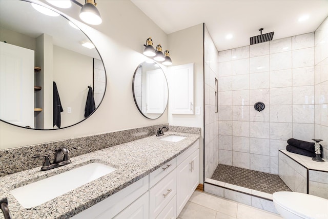 full bath with tile patterned flooring, a tile shower, toilet, and a sink