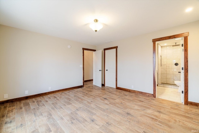 unfurnished bedroom with baseboards, light wood-style floors, and ensuite bathroom