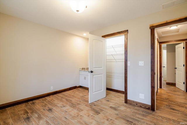 unfurnished bedroom with a closet, baseboards, and light wood finished floors