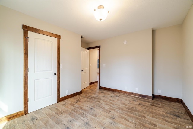 empty room featuring baseboards and light wood finished floors