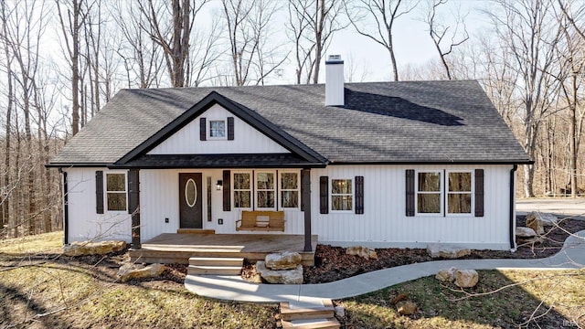 modern farmhouse style home with a porch, a chimney, and a shingled roof