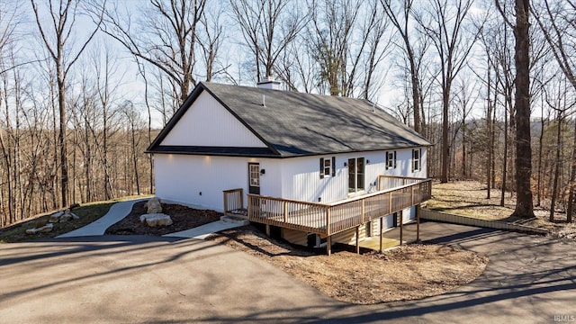 view of front of house with a chimney, a shingled roof, and a deck