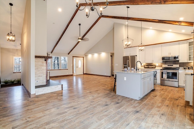 kitchen featuring open floor plan, stainless steel appliances, light wood-style floors, white cabinetry, and a sink