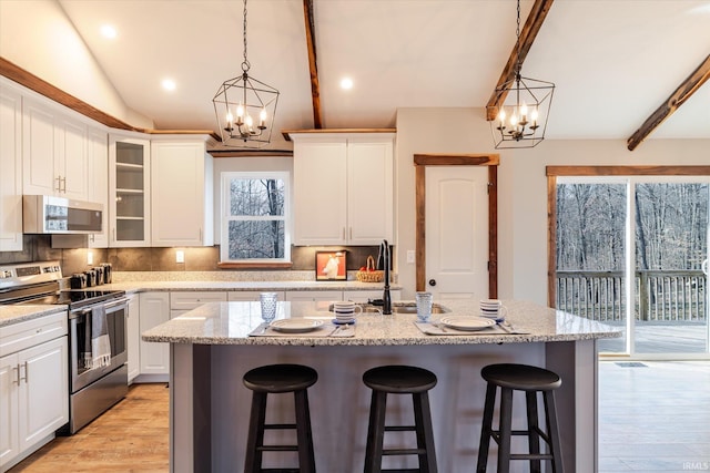 kitchen featuring a chandelier, a breakfast bar area, appliances with stainless steel finishes, and vaulted ceiling with beams