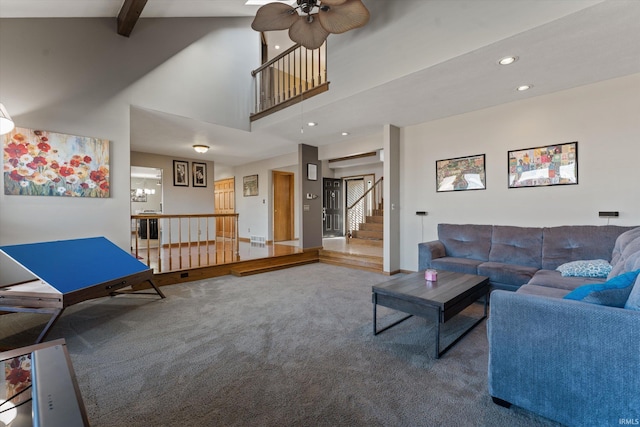 carpeted living area with stairway, beam ceiling, recessed lighting, a high ceiling, and a ceiling fan