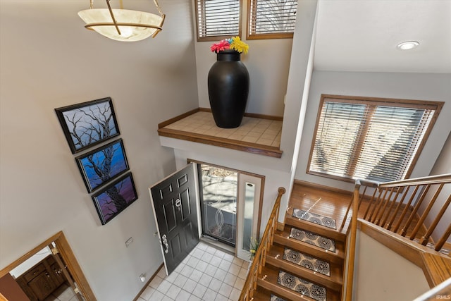 entryway with stairs, light tile patterned flooring, and baseboards