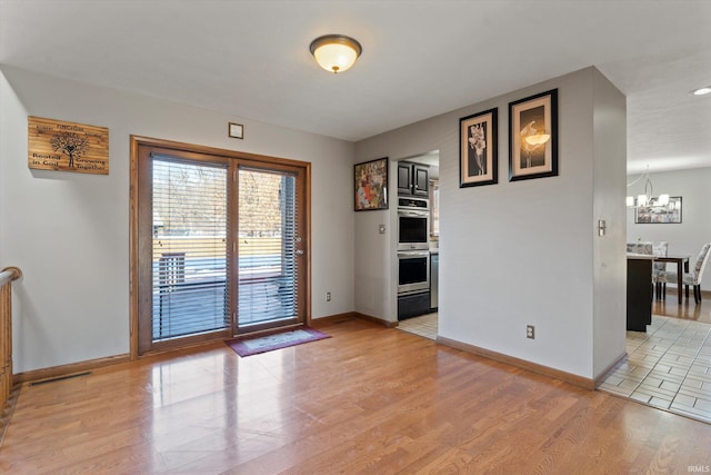 interior space featuring visible vents, baseboards, light wood-style floors, and a chandelier