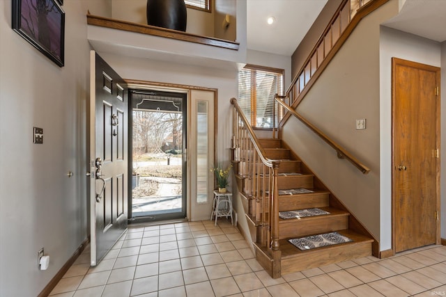 entryway featuring light tile patterned floors, stairway, and baseboards