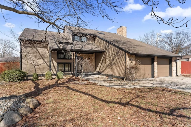 view of front of home featuring driveway, a chimney, and a garage